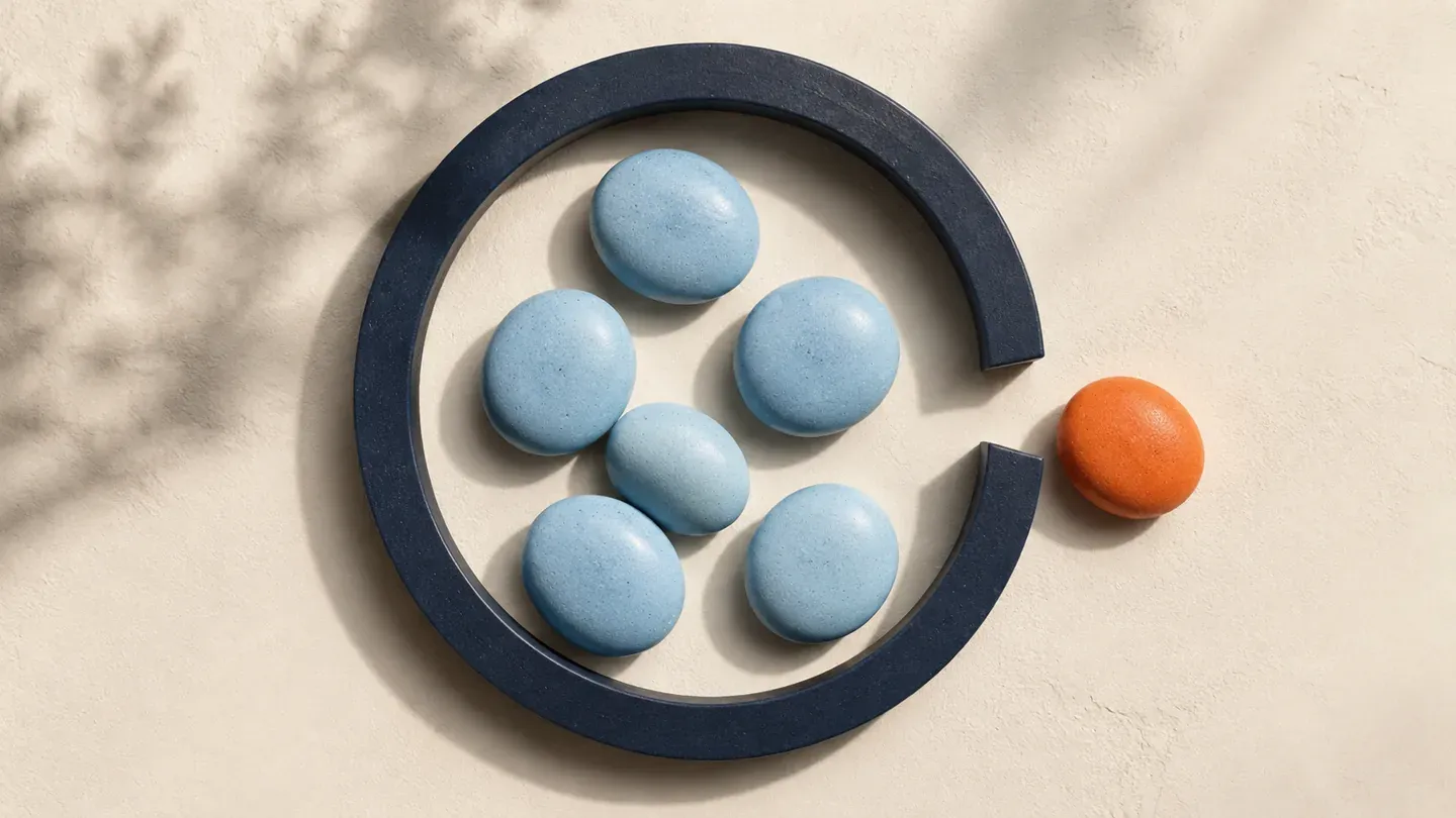 An orange pebble sits outside a gap in a navy ring containing blue pebbles.